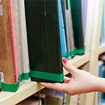 dłoń ściągająca książkę z półki w bibliotece 