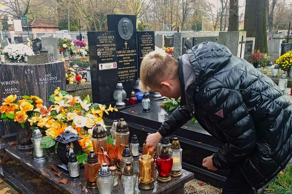 student zapalający znicz na grobie Jana Kałużnego