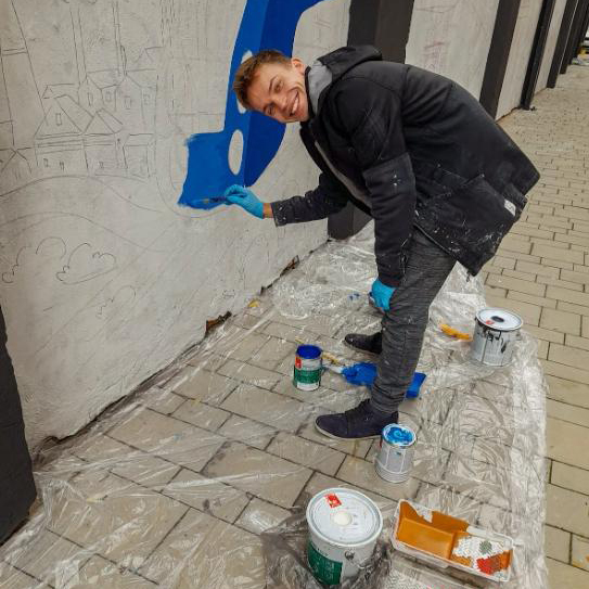 Maciej Skóra podczas malowania muralu
