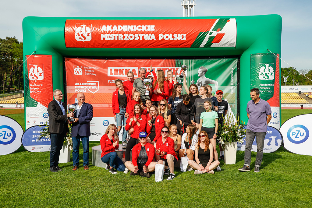 wspólne zdjęcie uczestników mistrzostw na tle pamiątkowej ścianki z napisem Akademickie Mistrzostwa Polski