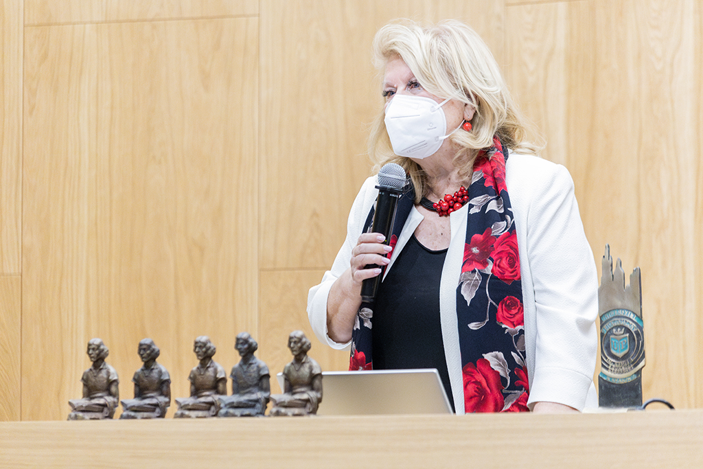 prof. zw. dr hab. Maria Pąchalska z mikrofonem w dłoni, na pierwszym planie stoją uniwersytecka rzeźba i figurki Copernicus Prize 2023