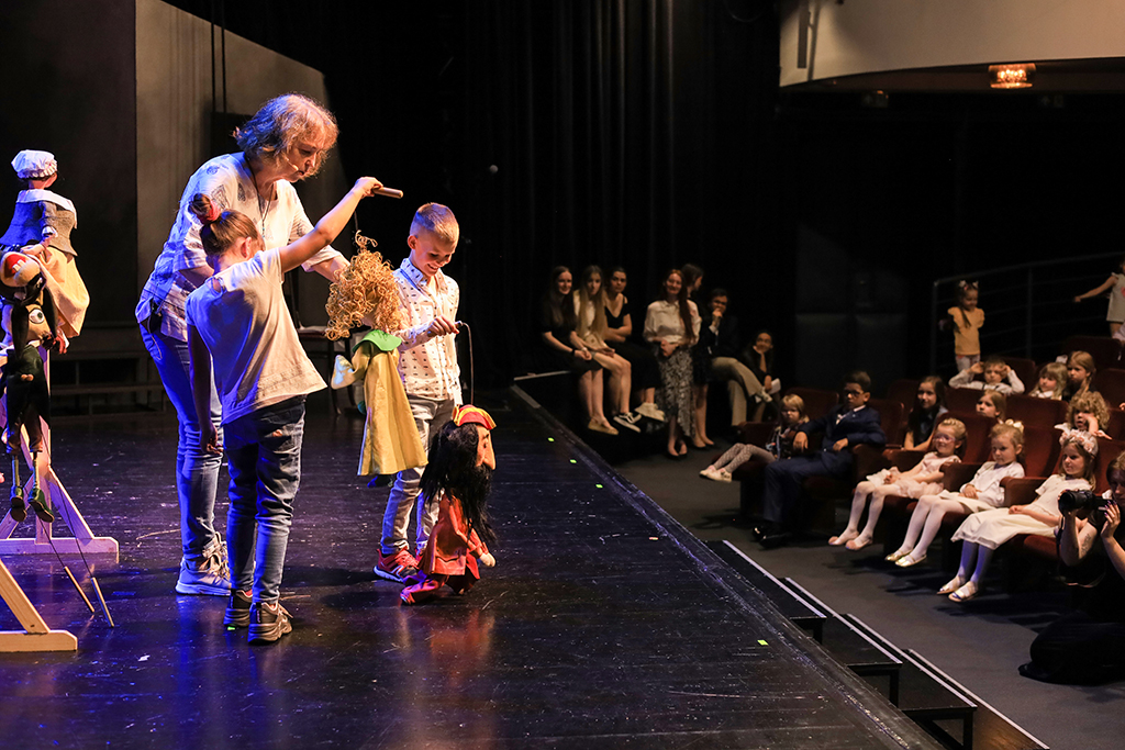 warsztaty teatralne „Tajniki sceny”, na pierwszym planie prowadząca – Ilona Buchner i dzieci z teatralnymi lalkami w rękach