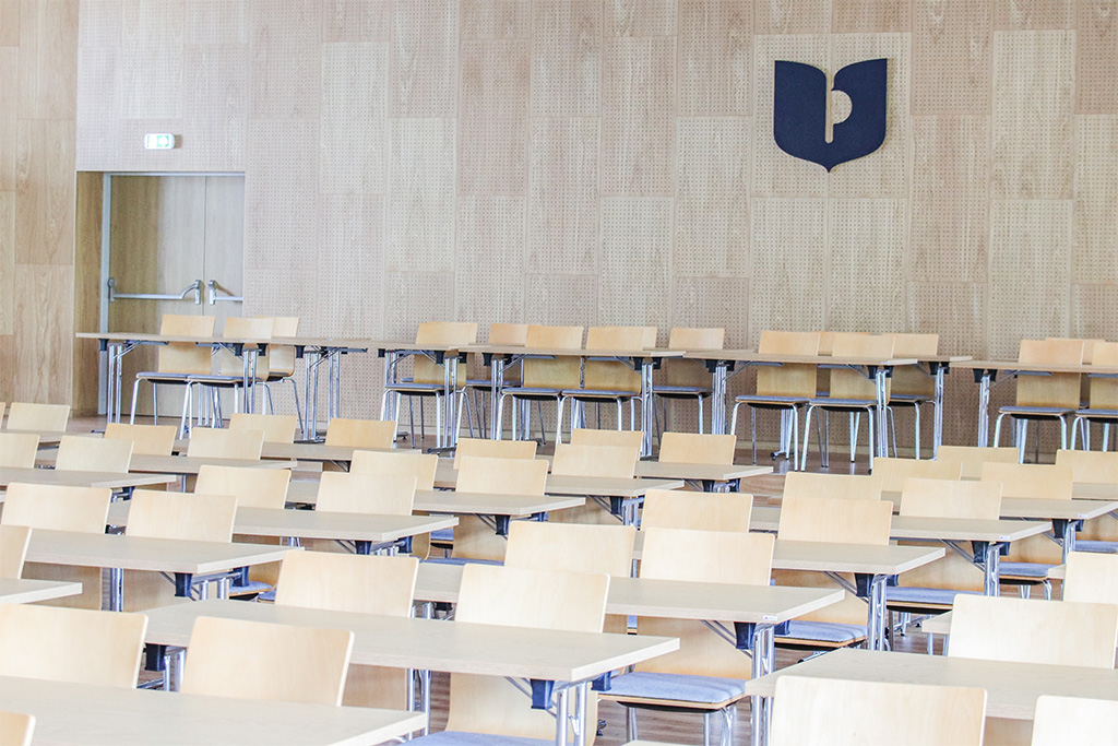 aula uniwersytecka wypełniona stolikami i krzesełkami