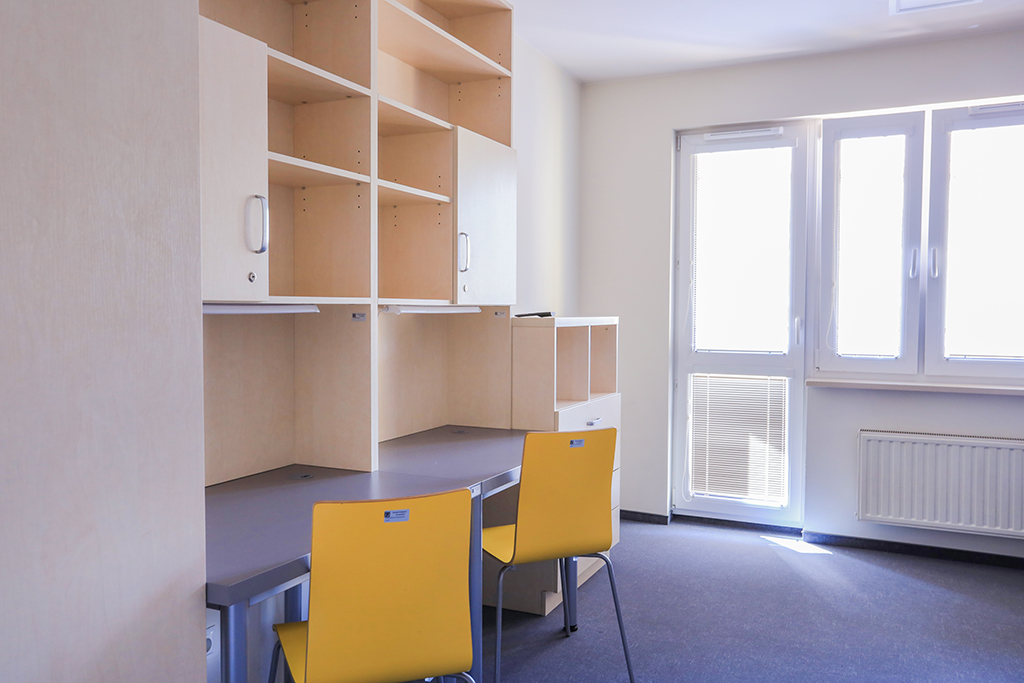 wnętrze pokoju w jednym z akademików; 2 biurka, 2 krzesła i półki na książki
